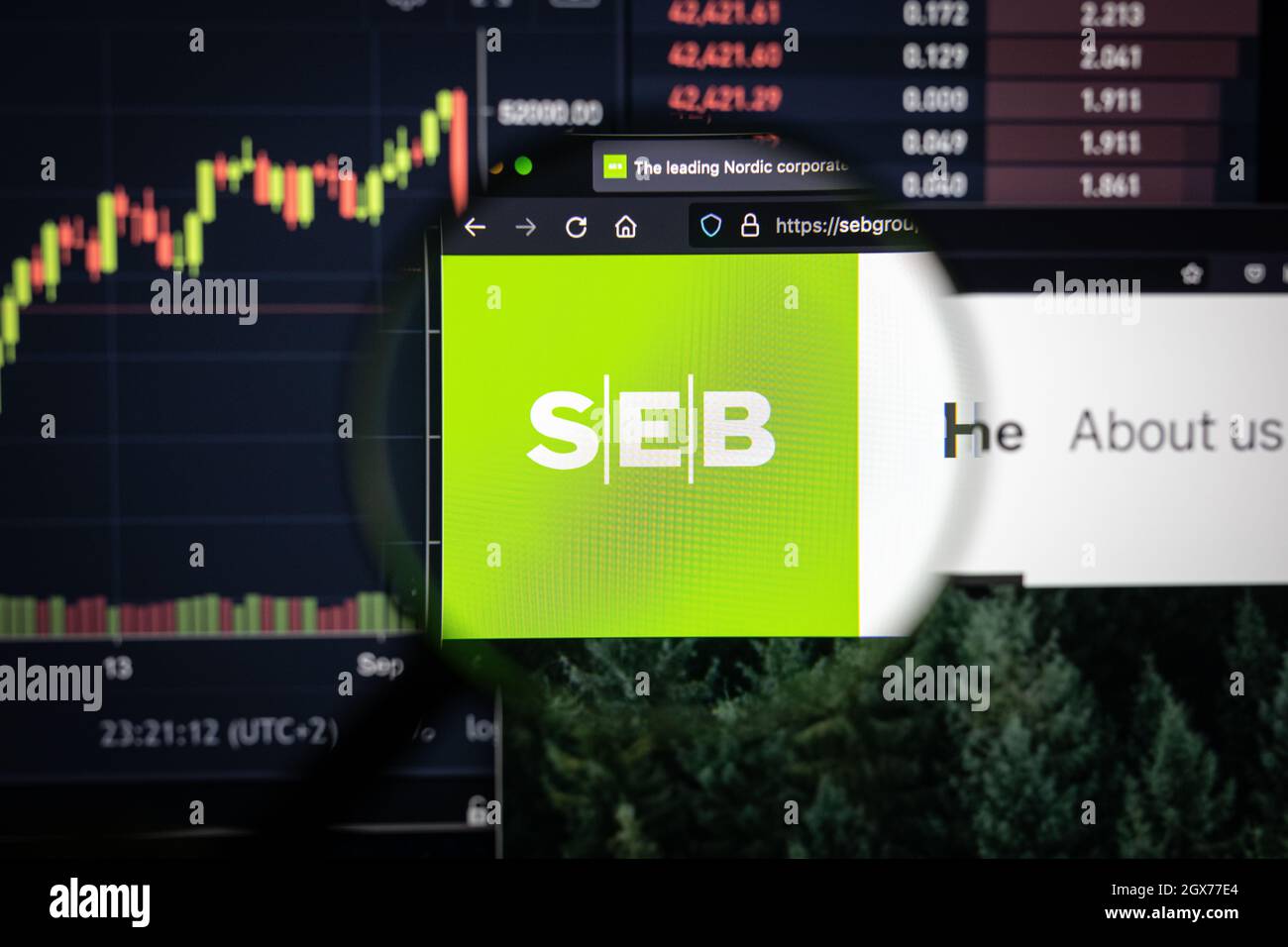 SEB company logo on a website with blurry stock market developments in the background, seen on a computer screen through a magnifying glass Stock Photo