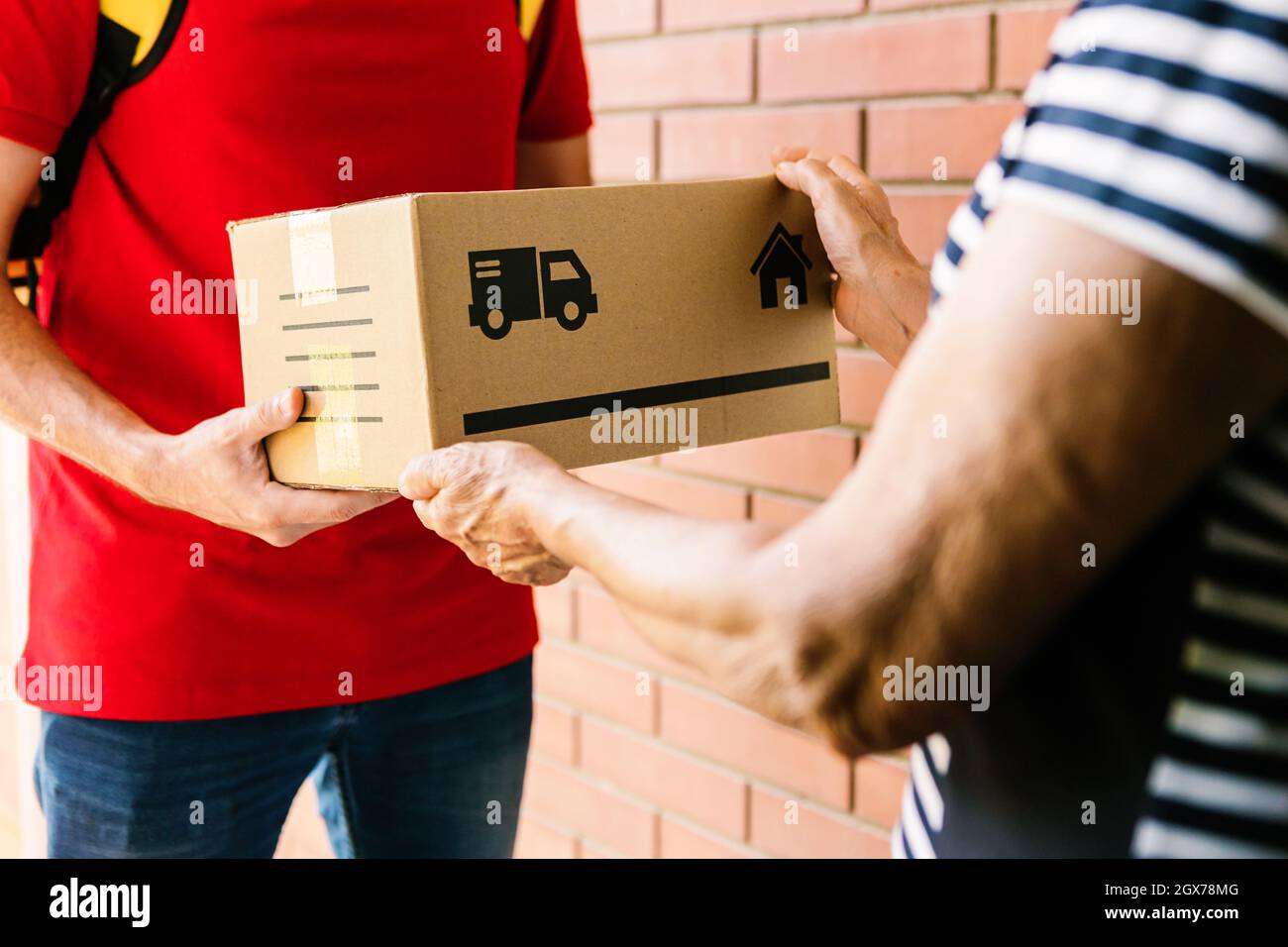 Postman delivering package to costumer - Senior woman receiving a parcel at home Stock Photo