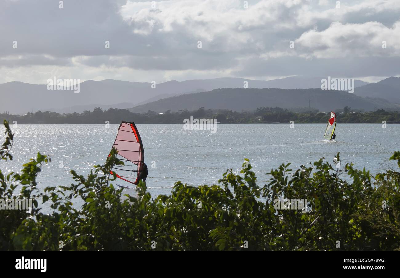 Young and elderly people practicing kite surfing and windsurfing in Ibiraquera lagoon. Stock Photo