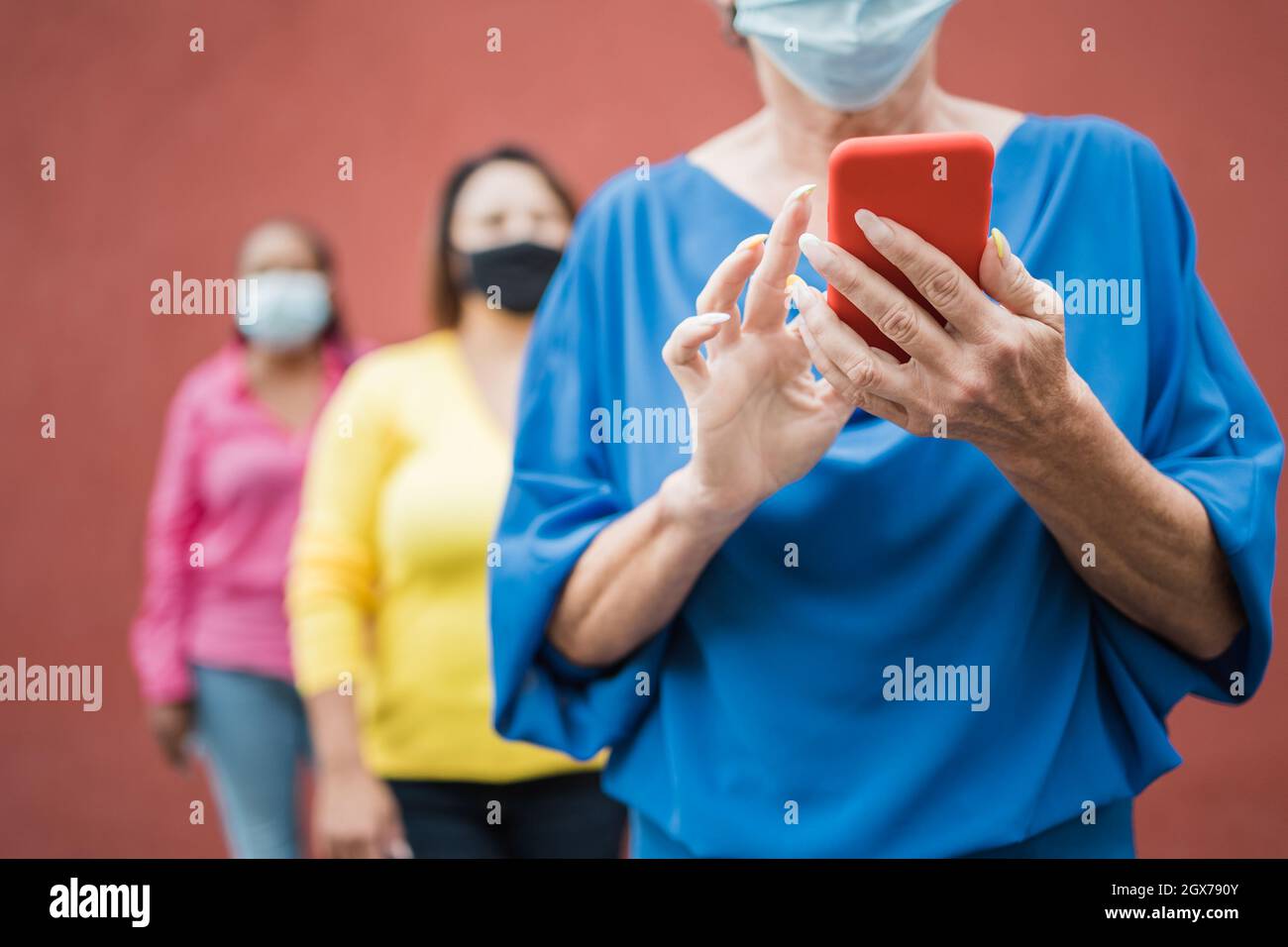 Group of senior people waiting in line while keeping social distance during coronavirus pandemic time - Elderly women wearing safety masks in the city Stock Photo