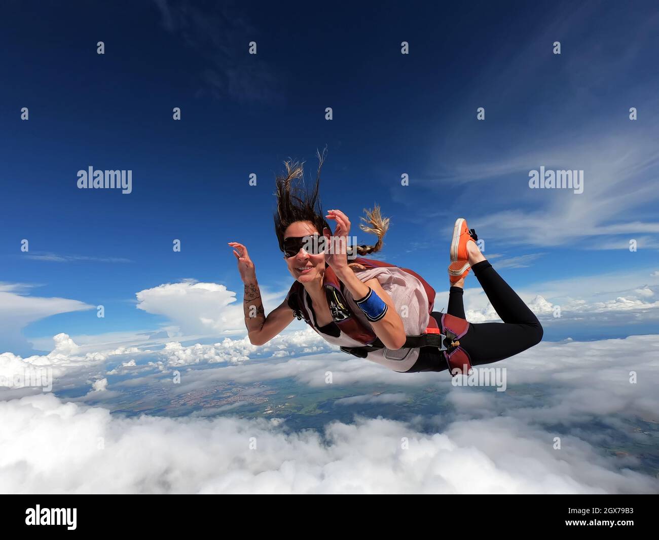 Young woman parachutist smiling in free fall. Perfect concept of happiness and freedom. Stock Photo