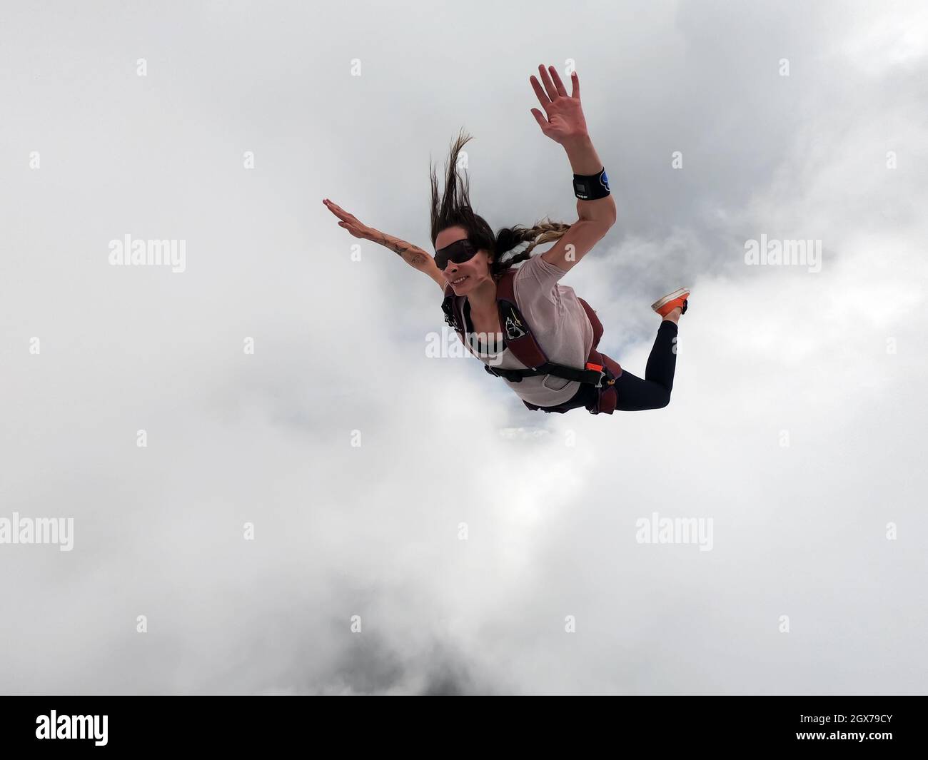 Young woman parachutist smiling in free fall. Perfect concept of happiness and freedom. Stock Photo