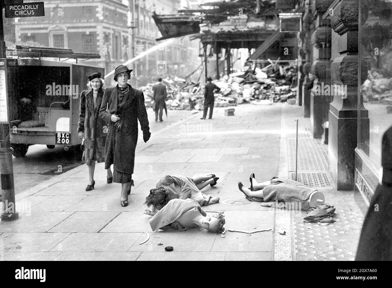 Ladies walk past shop dummies lying in the street after an air-raid in London during the Blitz in 1940 Stock Photo