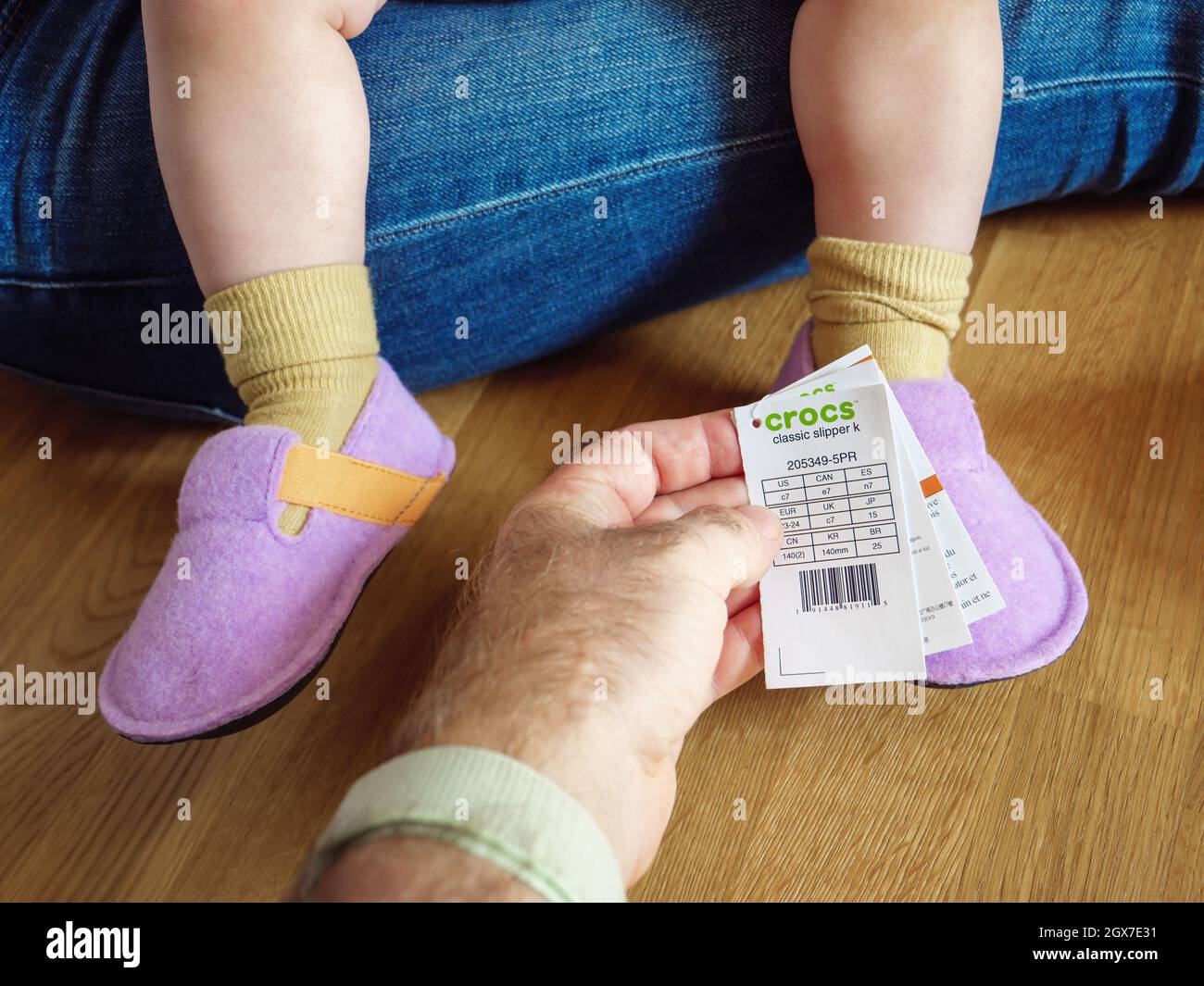 Man hand holding price tag and size tag of Crocs shoes for babies Stock  Photo - Alamy