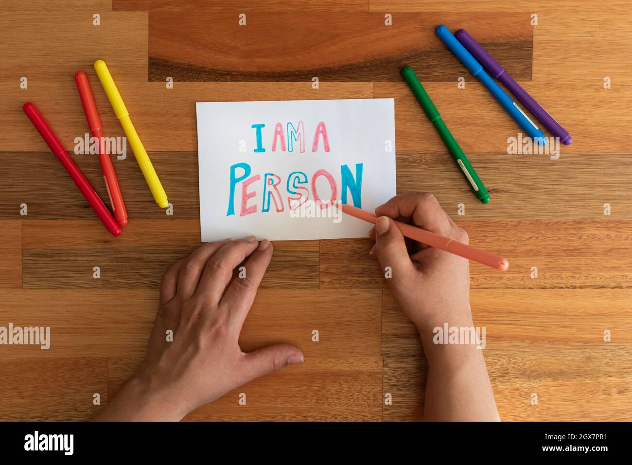 a woman's hands writing a sign that says 'i am a person' in transgender colors. Stock Photo