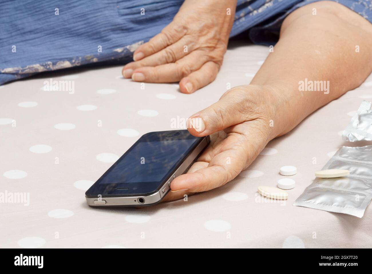 Elderly woman sleeping in bed and holding a mobile phone. Stock Photo