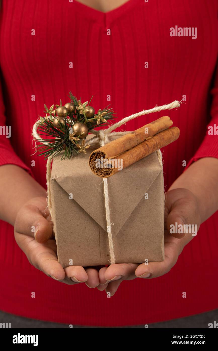 hands of a person holding a gift decorated with a ribbon, Christmas ornament and cinnamon stick, object, give details on special occasions, lifestyle Stock Photo