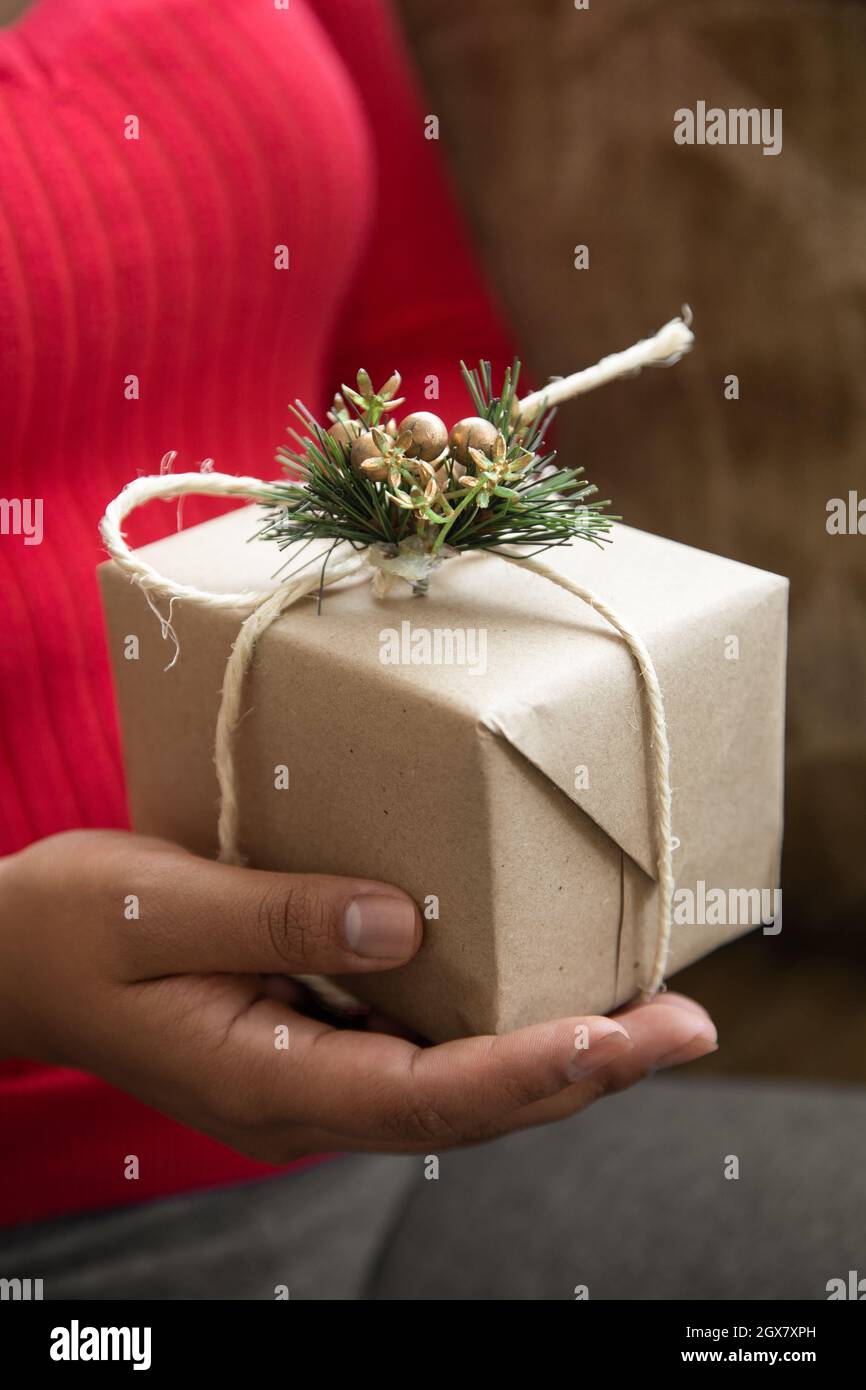 detail of a person's hands holding a gift decorated with a ribbon, Christmas ornament and cinnamon stick, share details on special occasions Stock Photo