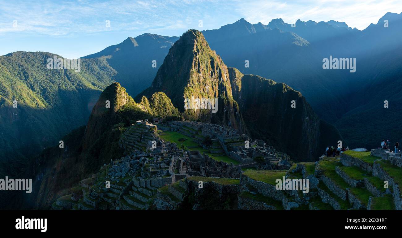 Machu Picchu panorama at sunrise with first sun rays illuminating the inca ruin, Peru. Stock Photo