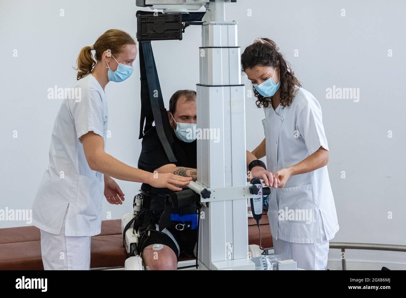 St Genis Laval (France), 4 October 2021. Rehabilitation session of a patient equipped with the HAL exoskeleton. Two nurses prepare the installation on Stock Photo
