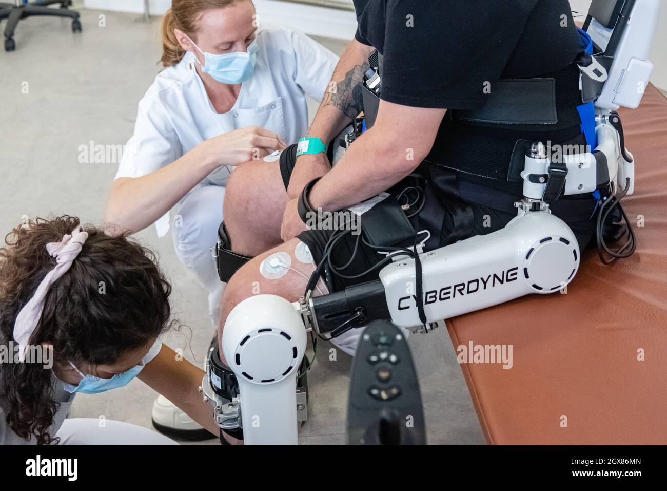 St Genis Laval (France), 4 October 2021. Rehabilitation session of a patient equipped with the HAL exoskeleton. Two nurses prepare the installation on Stock Photo