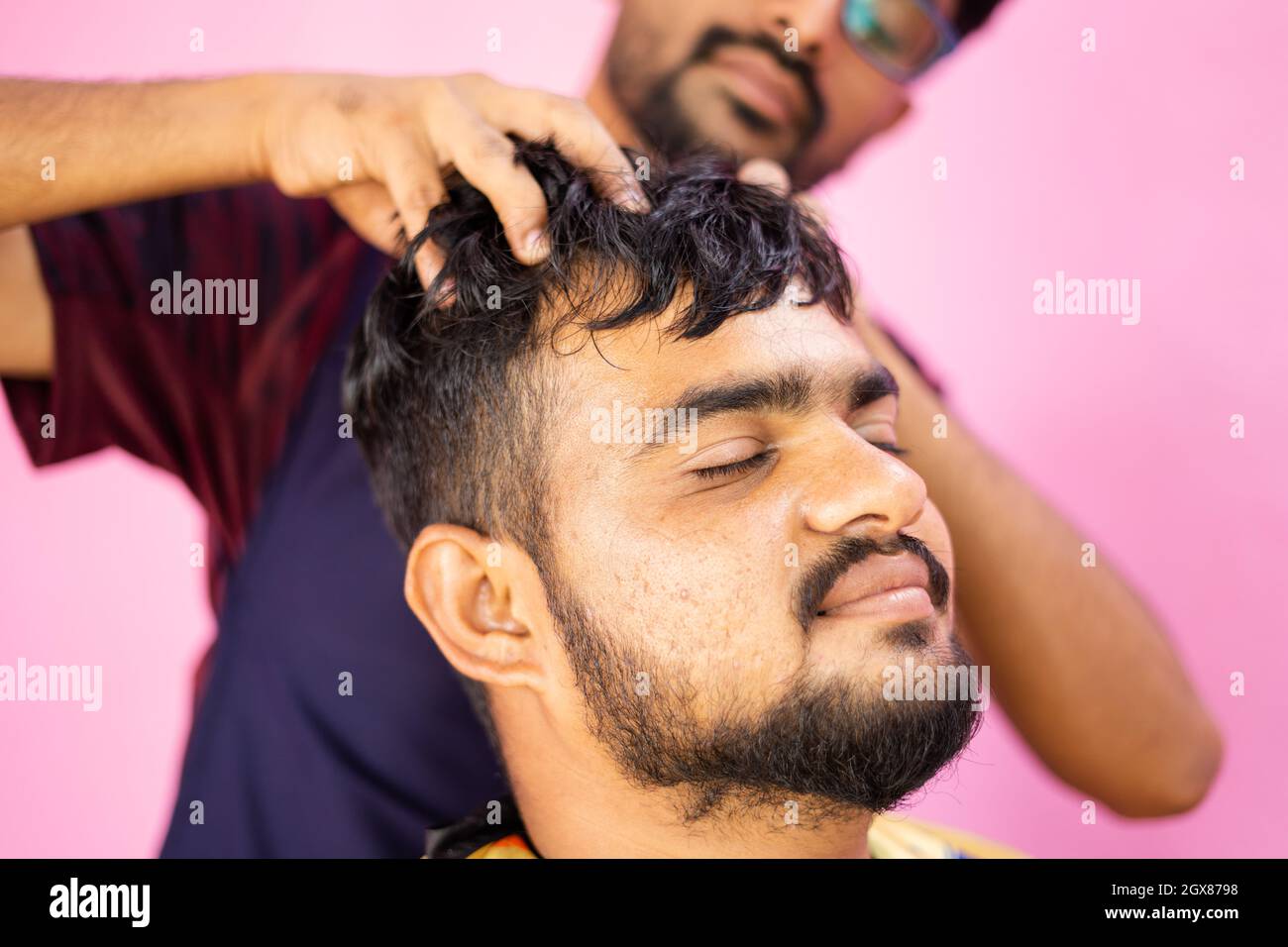 Customer at barber shop enjoying head massage from barber concept of