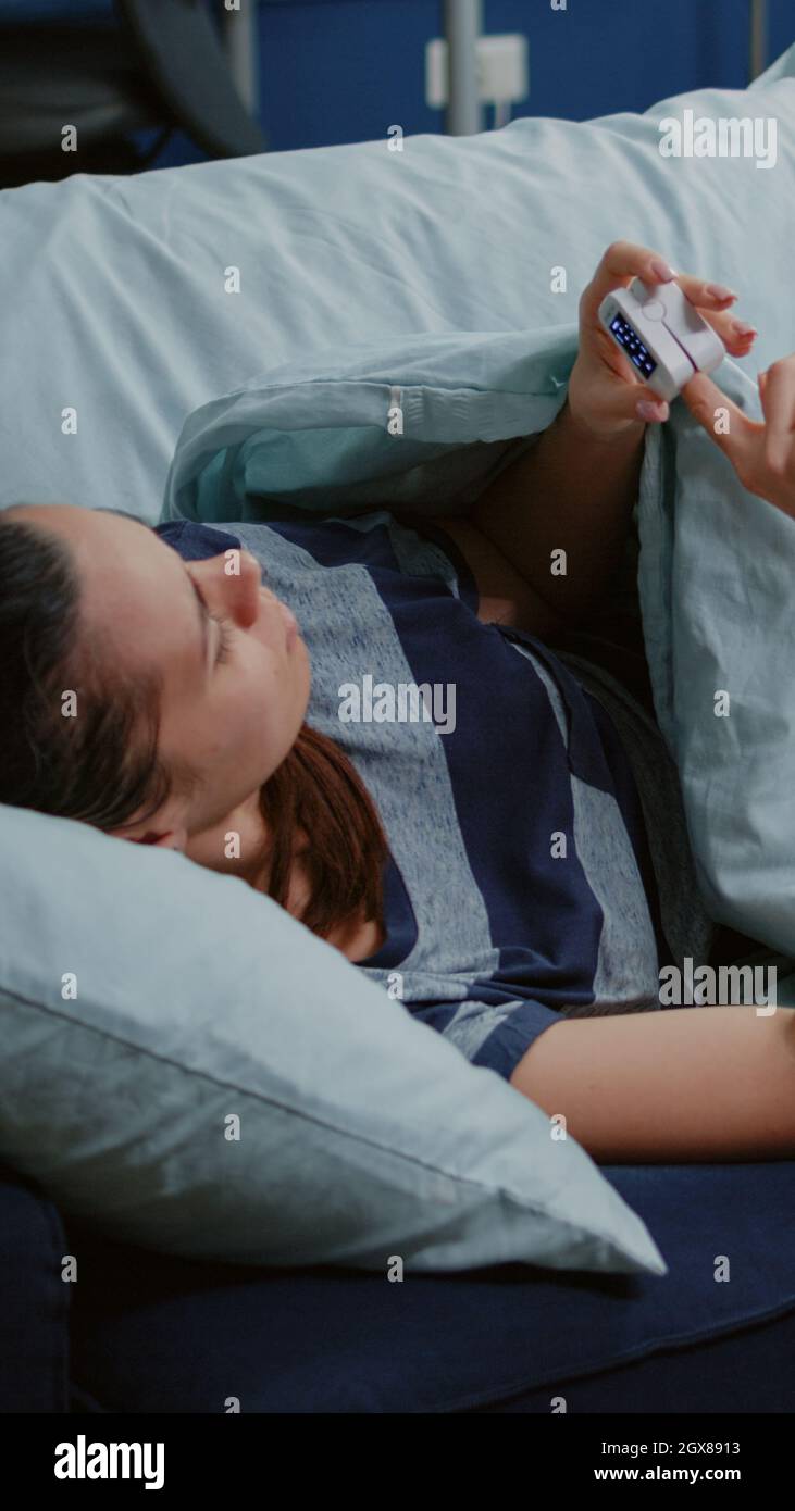 Sick person with fever using oximeter to measure pulse pressure and