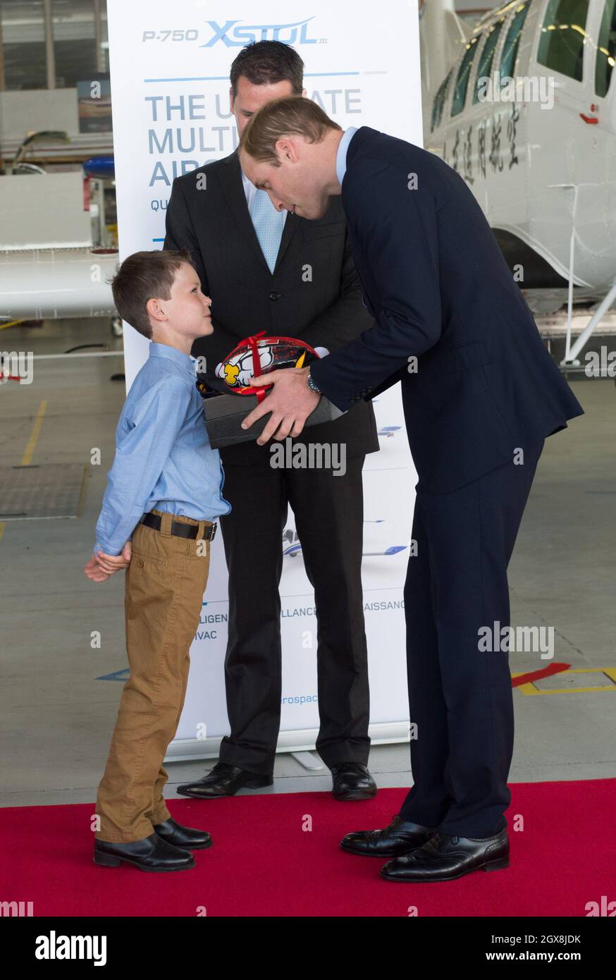 Prince William, Duke of Cambridge receives a gift from a boy during a visit to Pacific Aerospace in Hamilton, New Zealand Stock Photo