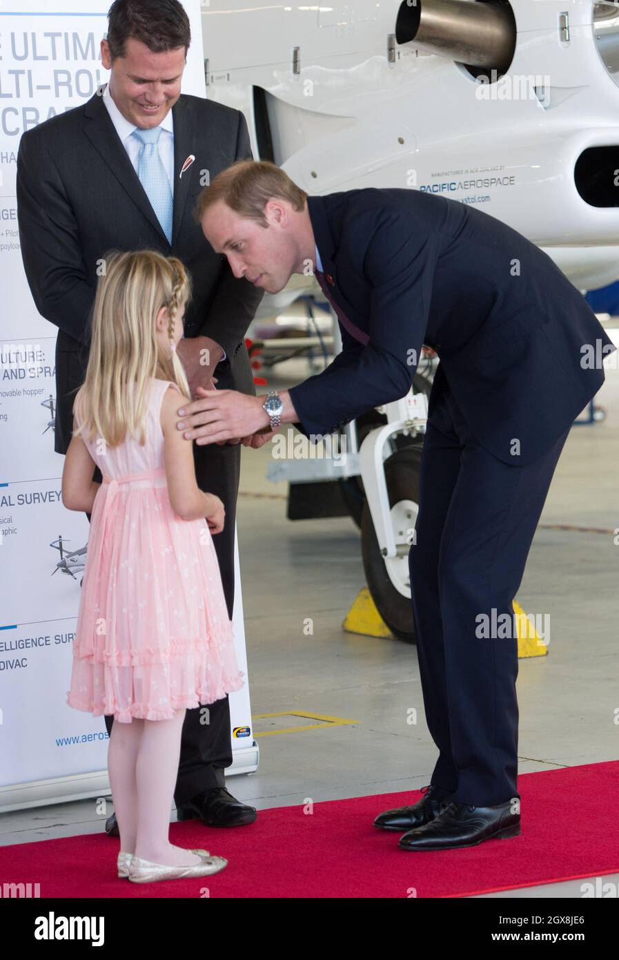 Prince William, Duke of Cambridge bends to talk to a girl during a visit to Pacific Aerospace in Hamilton, New Zealand Stock Photo
