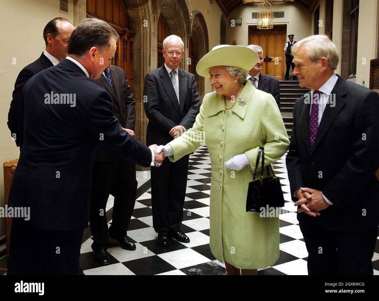 The Queen accompanied by the Presiding Officer George Reid (right) shakes hands with Scottish First Minister Jack McConnell at the Scottish Parliament in Edinburgh, where she was meeting party leaders. 3/4 length, hat, Royals  Stock Photo