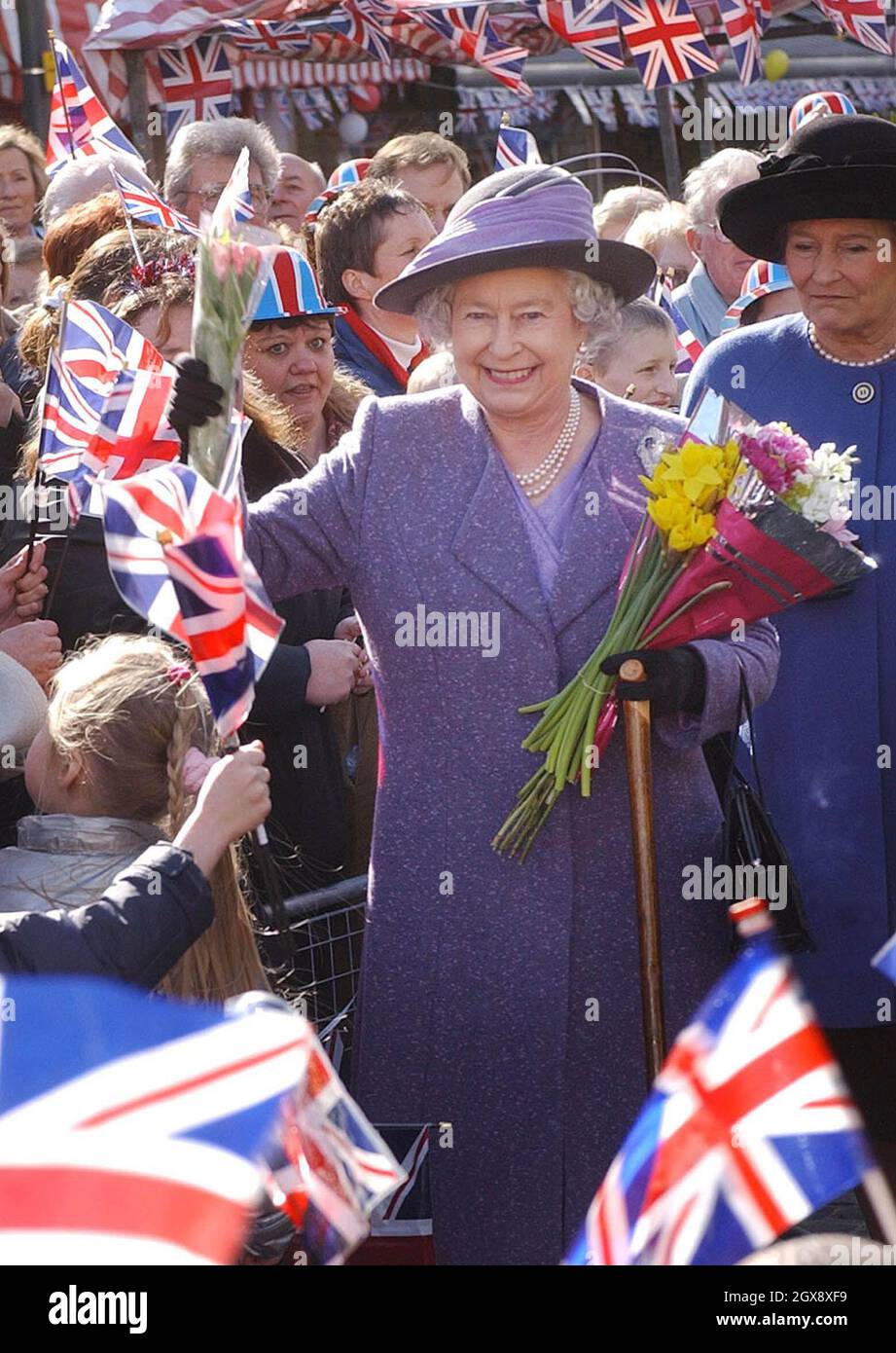 The Queen meets well wishers during a walkabout in the market square, Romford, Thursday March 6, 2003. The Queen, who has travelled the globe visiting some of the world's most famous destinations, has never before visited the area, famous for Cockney rhyming slang and its East End connections.  Three quarter length, royals, hat, flowers, union jack.  Â©Anwar Hussein/allaction.co.uk  Stock Photo