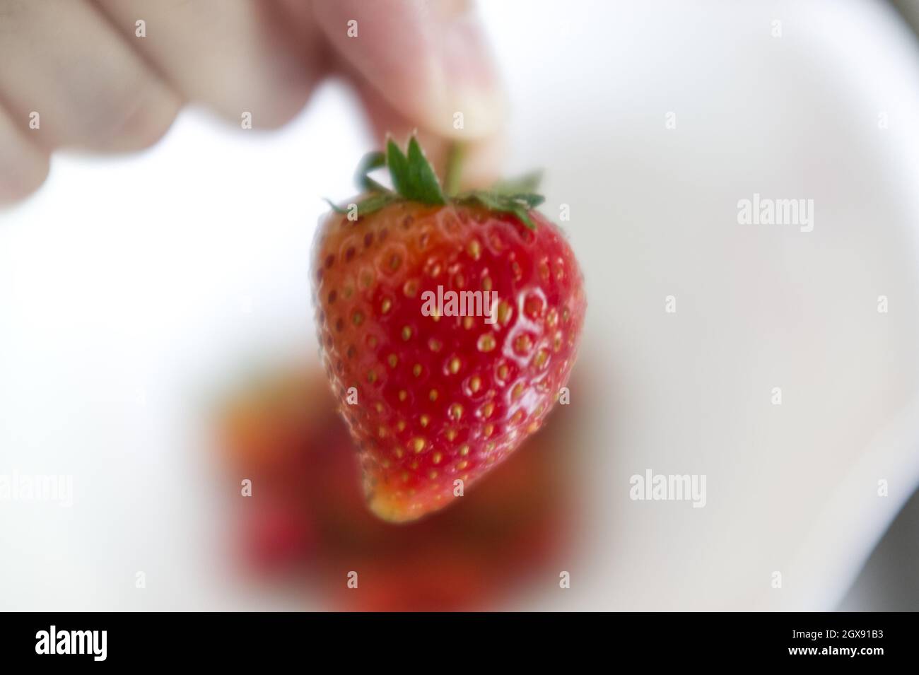 Hand holding strawberry on white background Stock Photo - Alamy