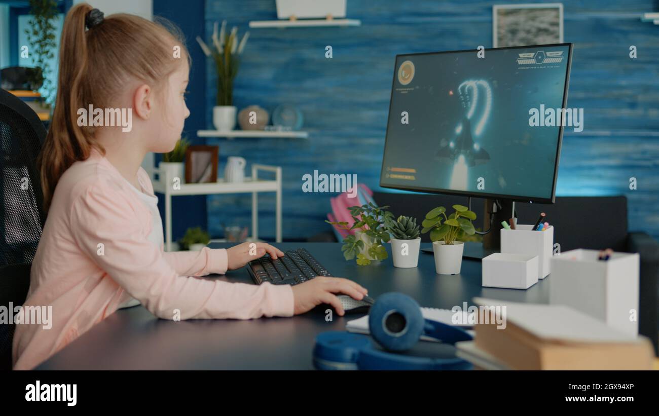 Young girl playing video games on computer after online school and  homework. Gamer using shooting action play for entertainment and fun with  keyboard and monitor. Child enjoying game Stock Photo - Alamy