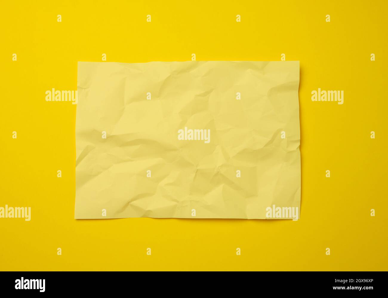 blank crumpled yellow sheet of paper on a yellow background, copy space