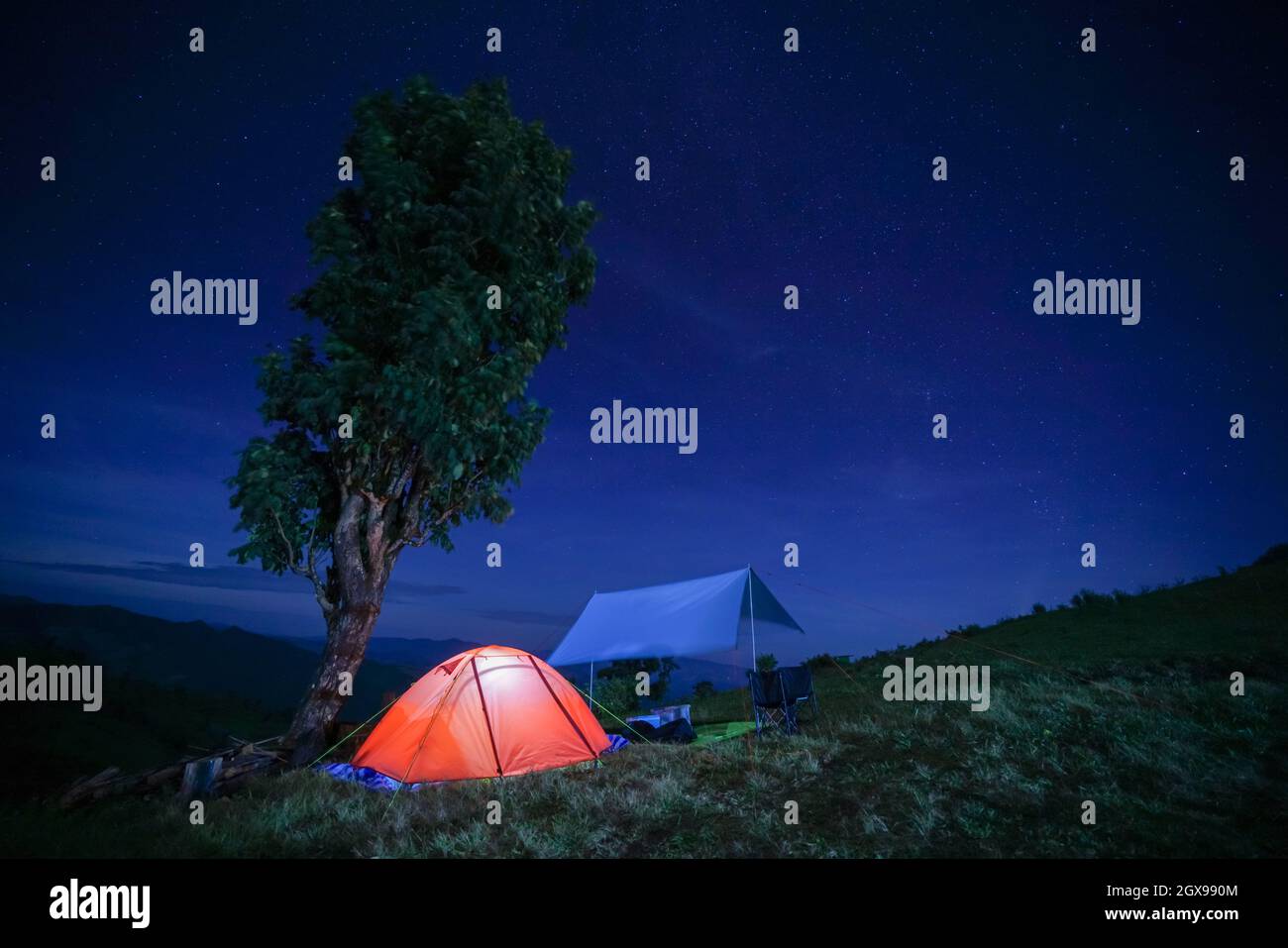 Glowing orange tent in the mountains under dramatic sky Stock Photo - Alamy