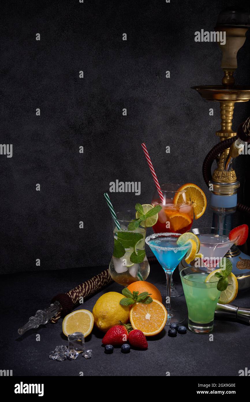 Hookah and cocktails set. Glasses with various cold beverages, fruits, shisha and bar tools on