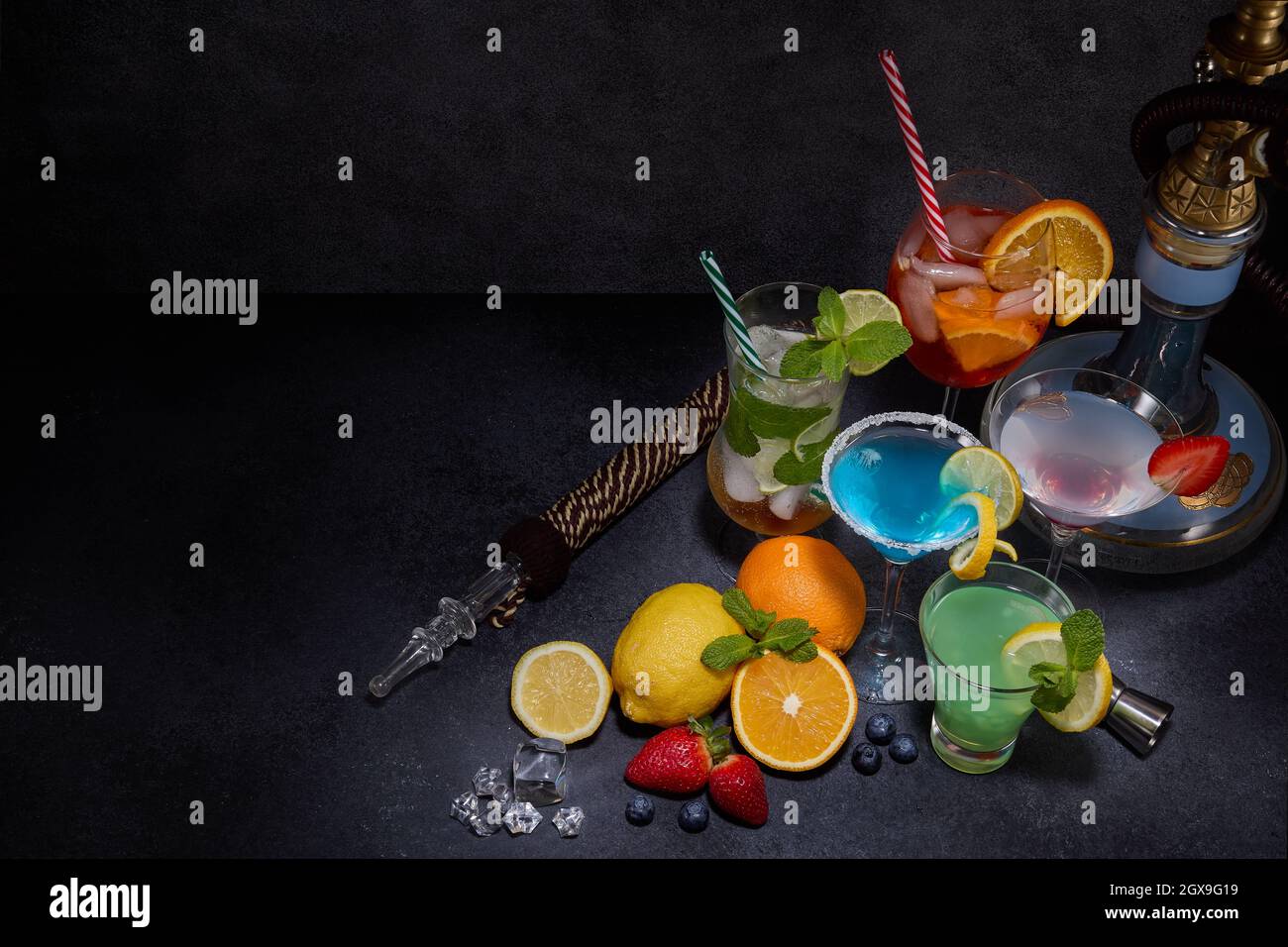 Hookah and cocktails set. Glasses with various cold beverages, fruits and shisha on dark grey