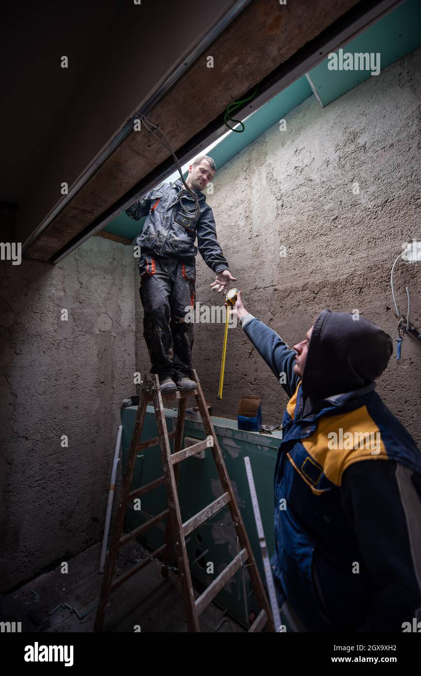 construction workers using ladder while installing environmentally ...