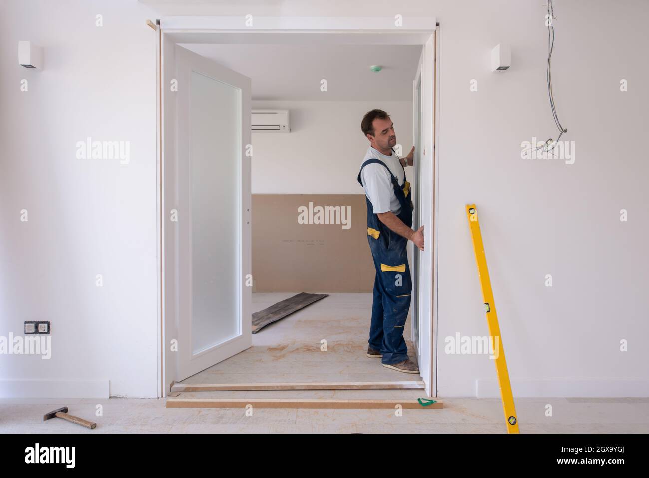 male workers carpenters installing interior glass door with a wooden
