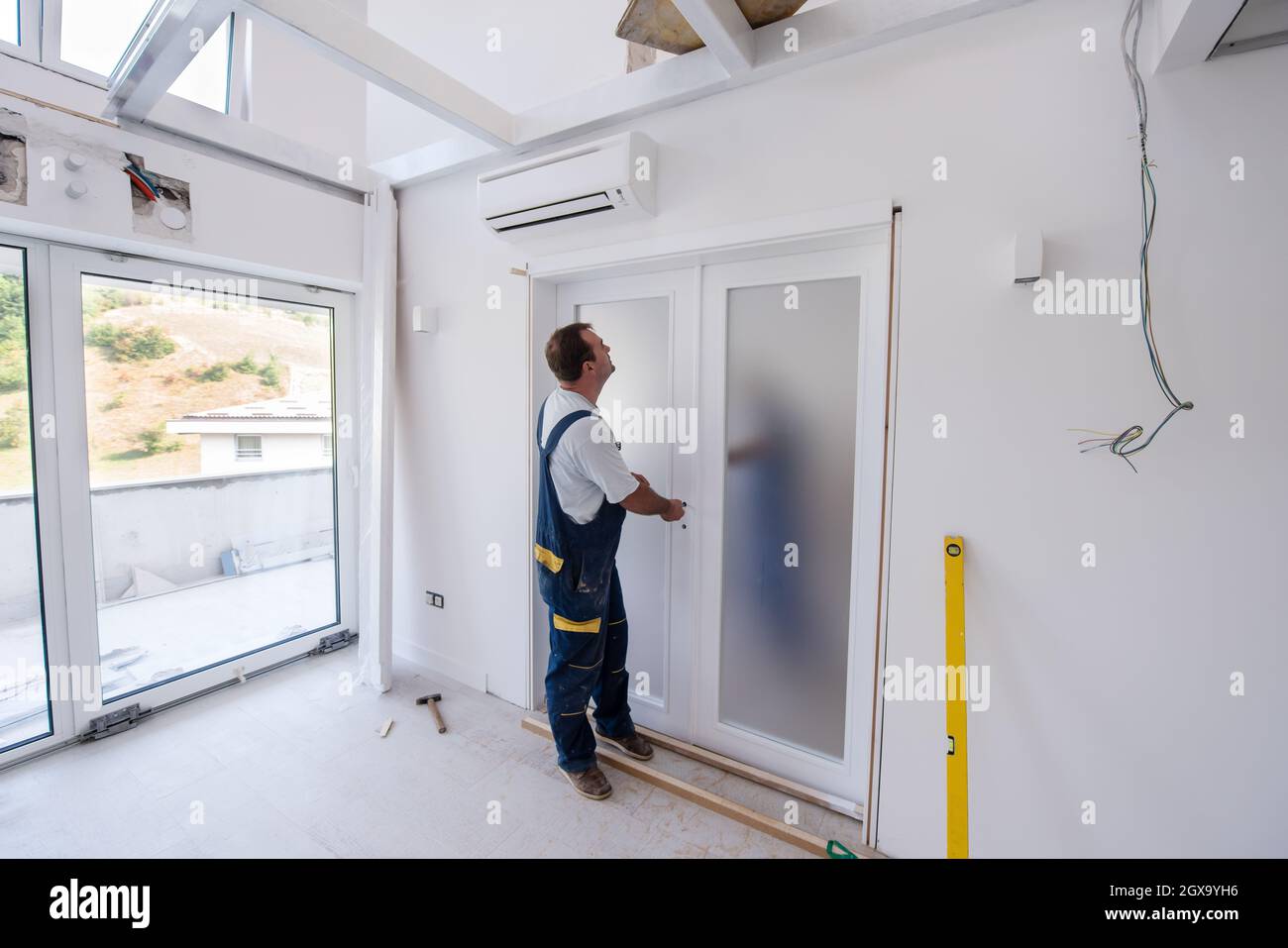 Image showcasing male workers carpenters installing interior glass door with a wooden ...