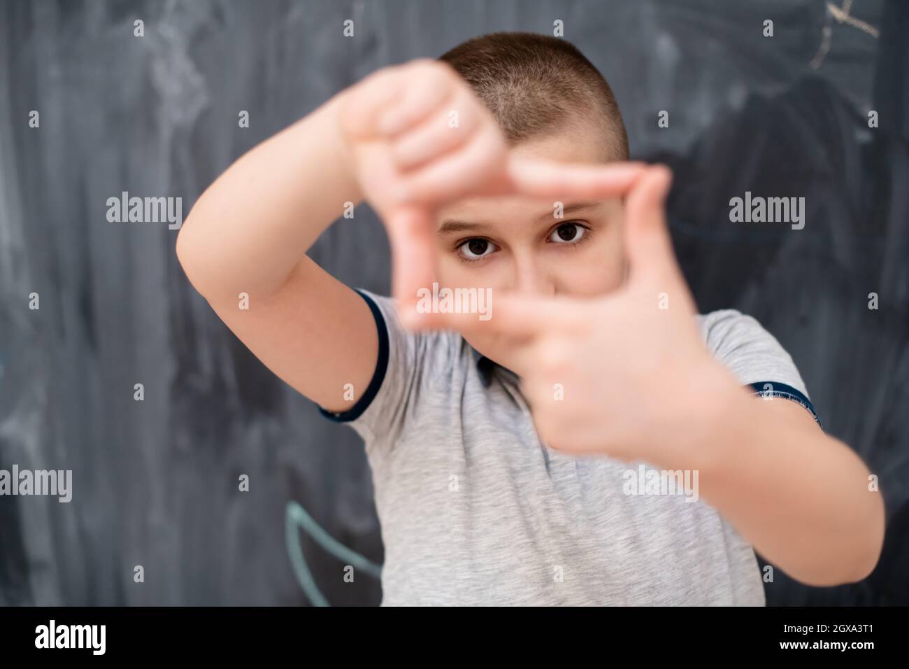 happy cute little boy having fun making hand frame gesture while ...