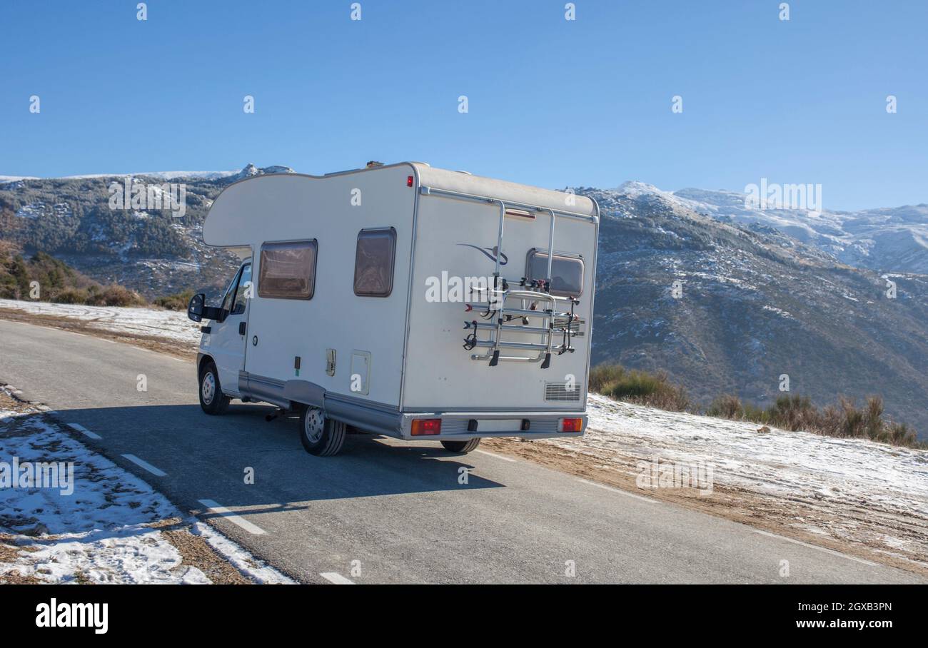 Motorhome climbing slowly by mountains pass. Rear outdoor view. Stock Photo