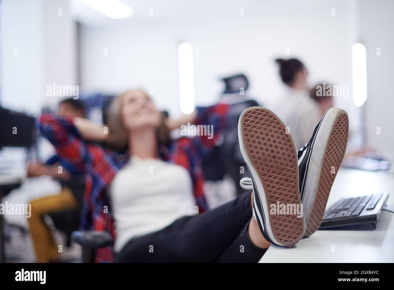 casual business woman taking a break with legs on her table while ...