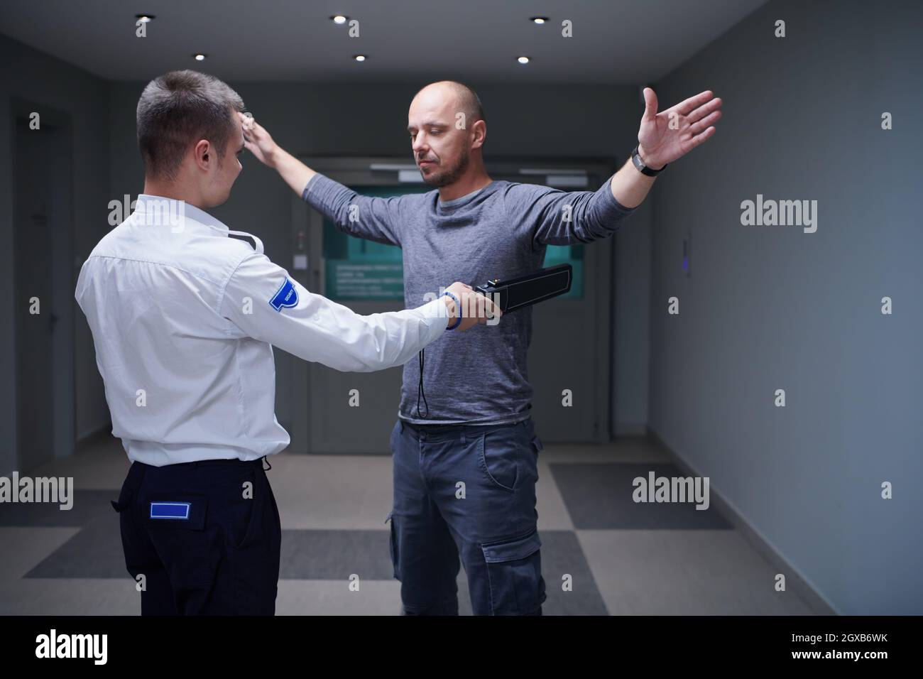 Security guard making body searching procedure with a metal detector on