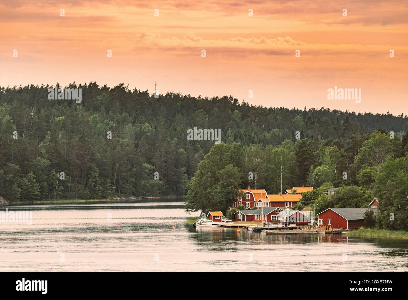 Sweden. Many Beautiful Red Swedish Wooden Log Cabins Houses On Rocky Island Coast. Lake Or River Landscape. Stock Photo
