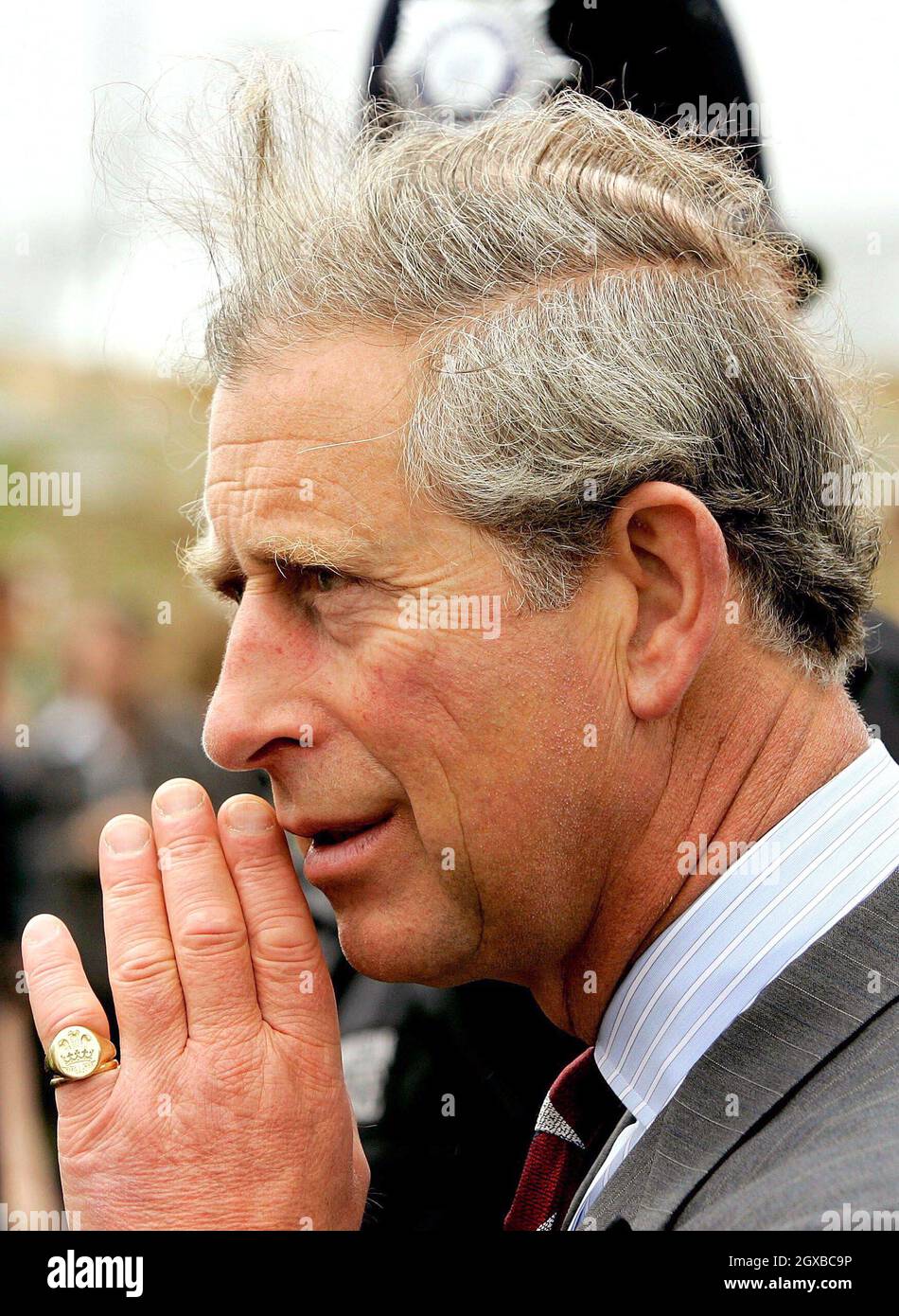 Charles, Prince of Wales, wearing a ring on his little finger, finds his  hair caught in a gust of wind during a walkabout at the Royal Arsenal  Woolwich housing project in London.