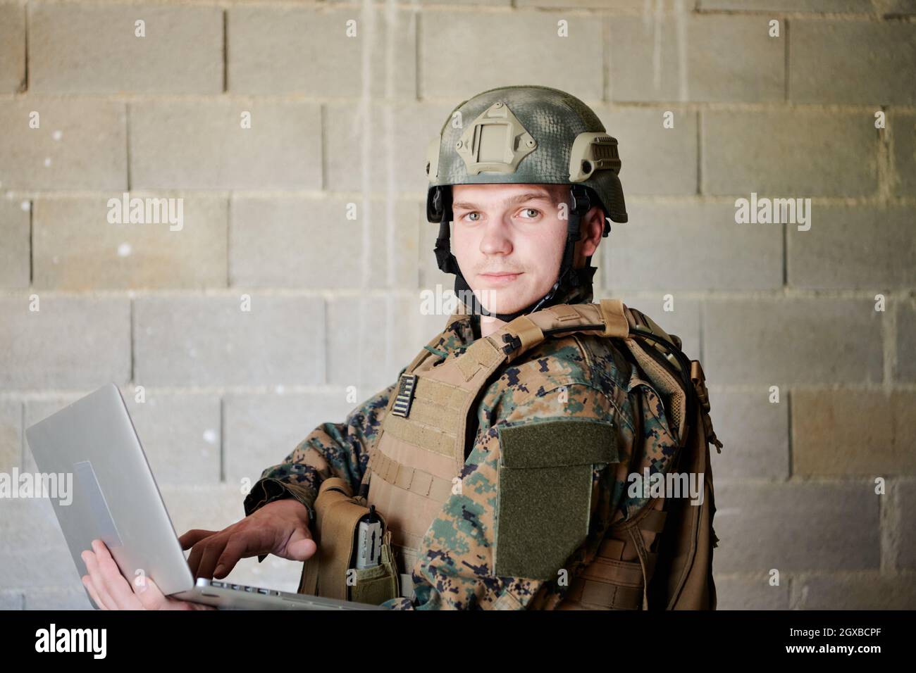 American soldier in military uniform using laptop computer for drone controlling and to stay in contact with friends and family Stock Photo