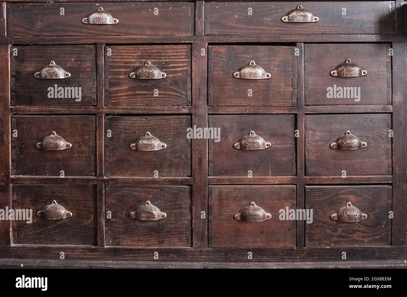 Dark brown wooden drawers furniture. Shell-shaped metal handles. Stock Photo