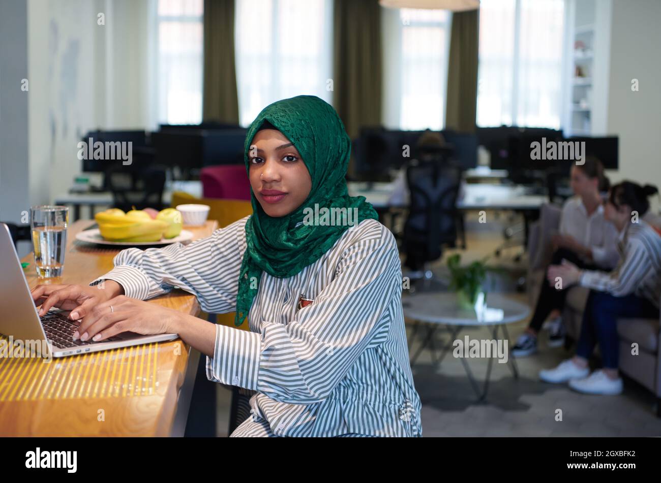 african muslim business woman wearing a green hijab while working on ...