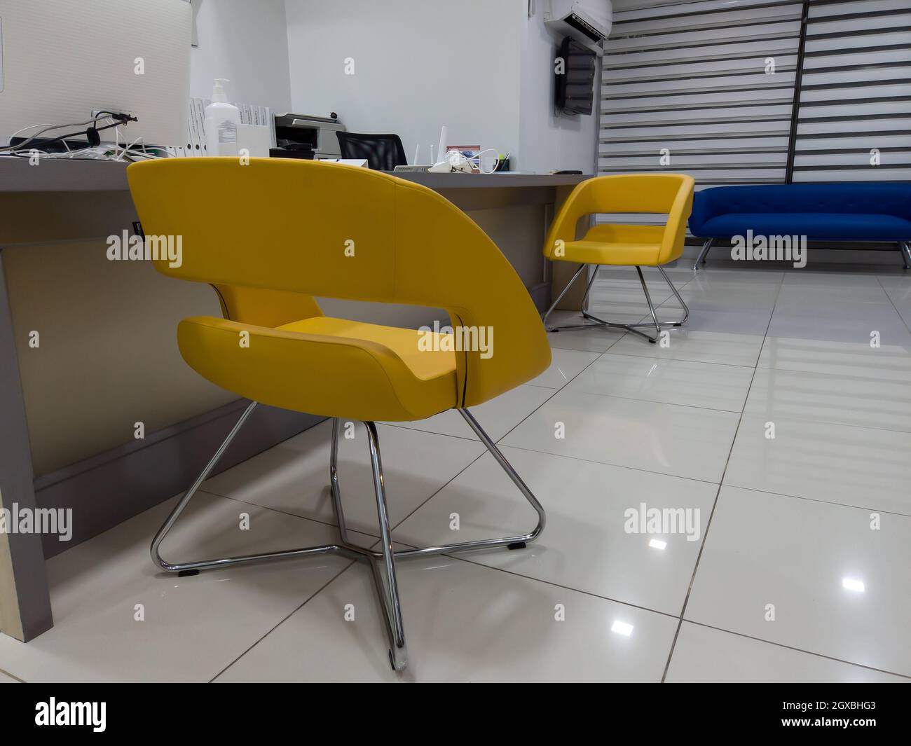 Interior of a modern waiting room with reception desk reception area. Yellow armchair for