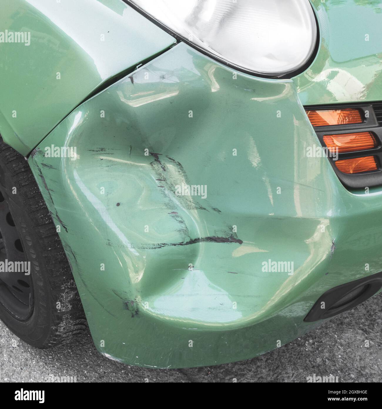 Green dented car. Side body of car was damaged by accident in traffic. Close-up. Stock Photo