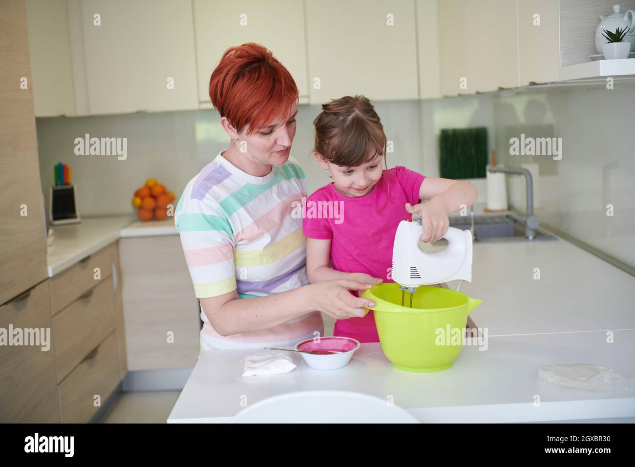 Happy family in the kitchen playing games and learning to cooking while staying at home during coronavirus covid-19 pandemic isolation. Mother and chi Stock Photo