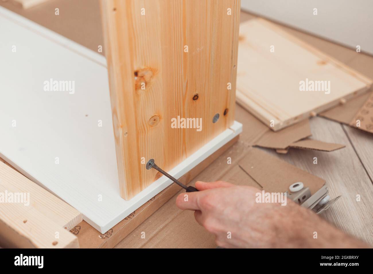 Assembling wooden furniture manually with screwdriwer. Stock Photo