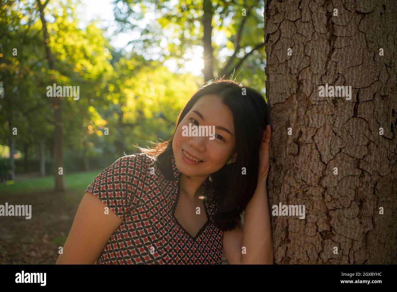 outdoors lifestyle portrait of young happy and beautiful Asian Korean woman enjoying relaxed and cheerful at city park in Autumn full of tree leaves o Stock Photo