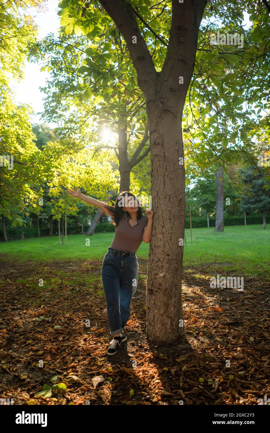 vertical outdoors lifestyle portrait of young happy and beautiful Asian Korean woman enjoying relaxed and cheerful at city park in Autumn full of tree Stock Photo