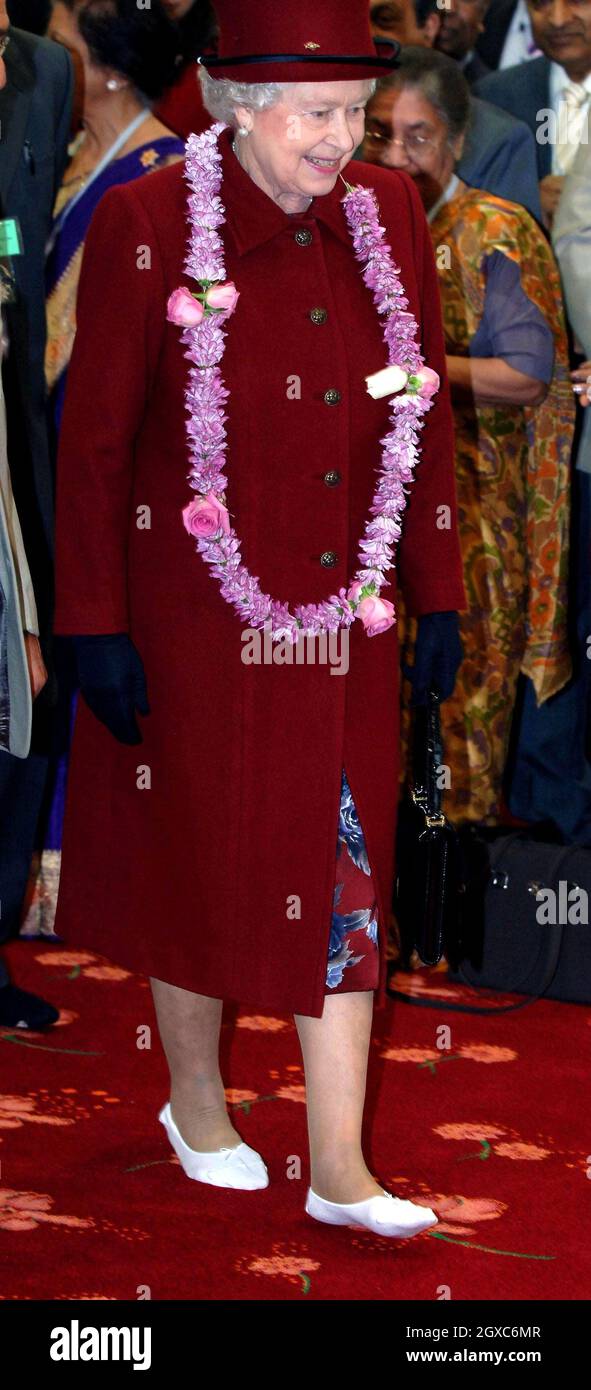 Queen Elizabeth II wears slippers and is presented with a garland when