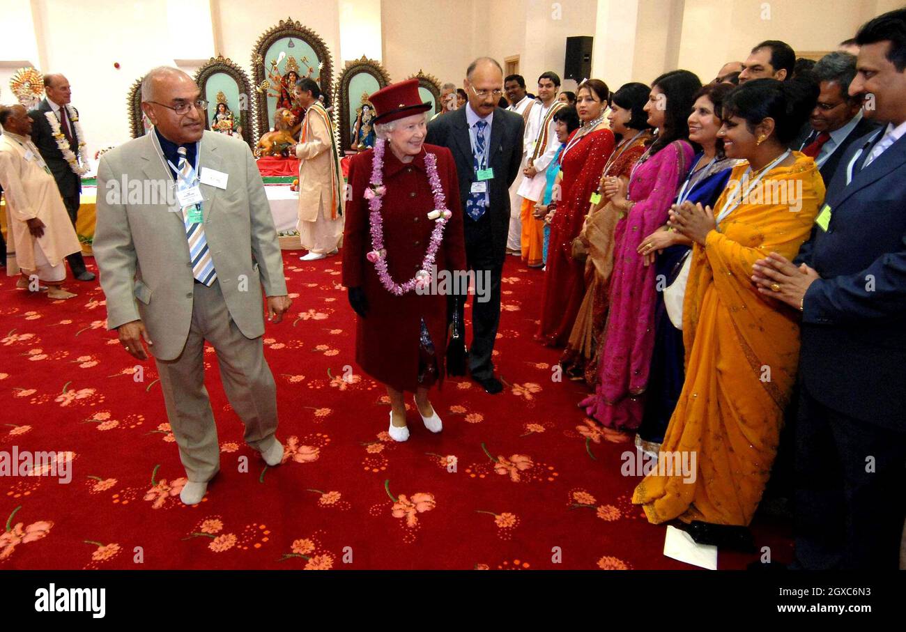 Queen Elizabeth II wears slippers and is presented with a garland when