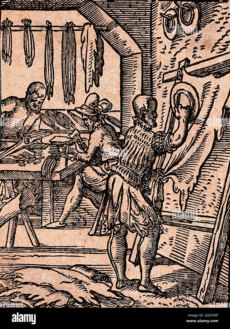 One man is rolling a circular object on a length of fabric on a stretcher as others work at a bench. Woodcut. - Type/Technique Woodcuts. Stock Photo