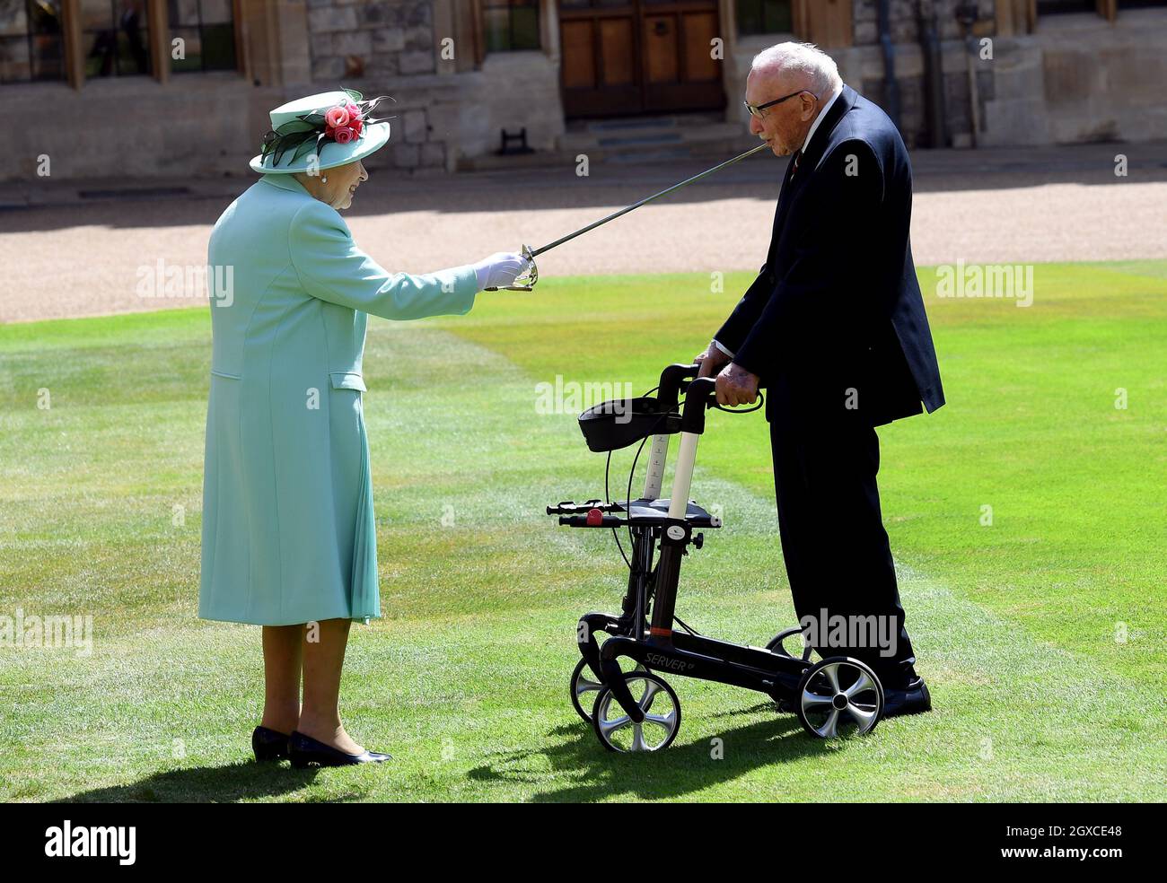 Queen Elizabeth II (using the sword that belonged to her father, King George VI) confers the Honour of Knighthood on 100 year old Captain Sir Thomas Moore before presenting him with the insignia of Knight Bachelor during an investiture ceremony at Windsor Castle on July 17, 2020. Captain Tom Moore raised over £32 million for the NHS during the coronavirus pandemic. Stock Photo