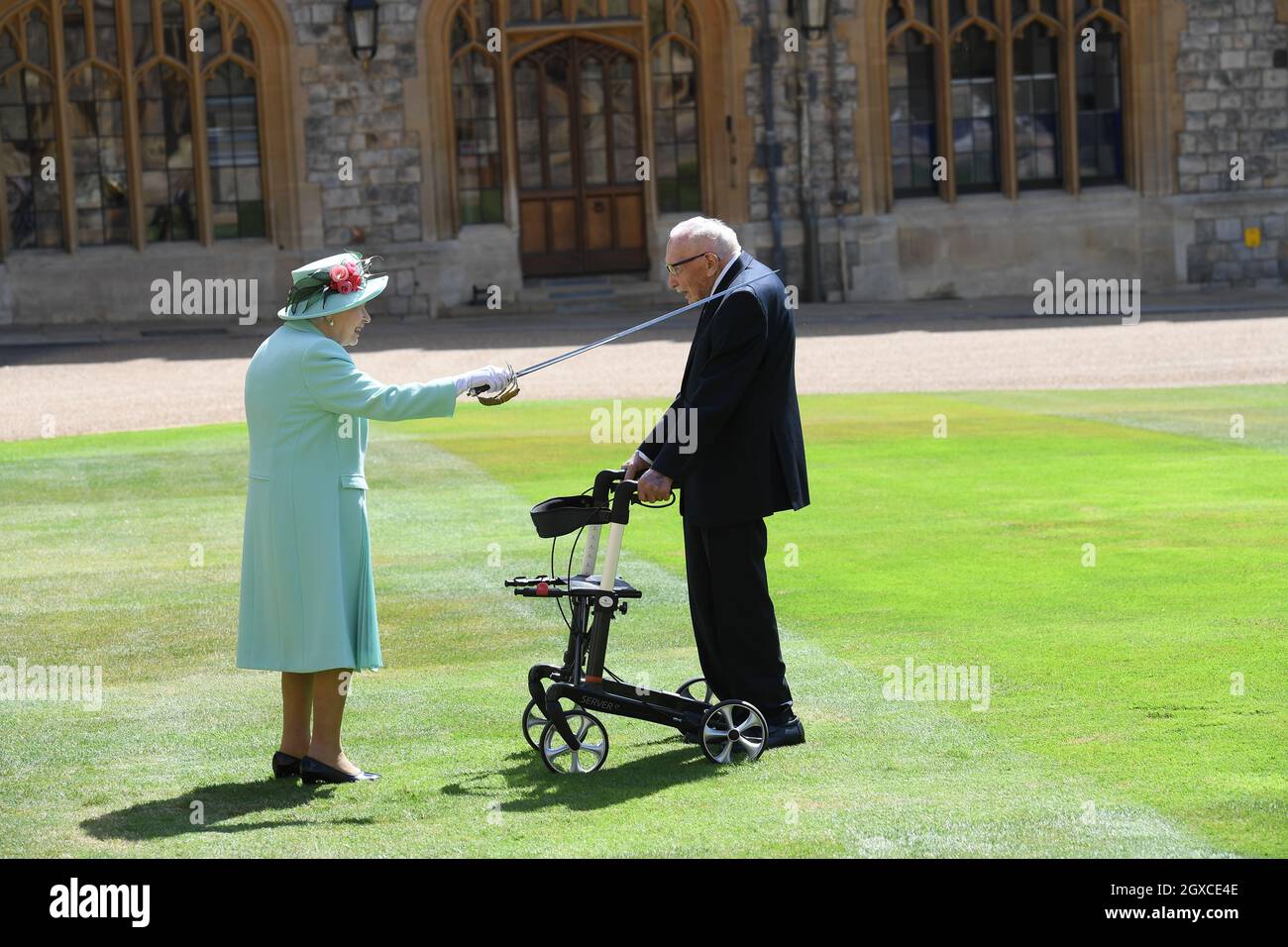 Queen Elizabeth II (using the sword that belonged to her father, King George VI) confers the Honour of Knighthood on 100 year old Captain Sir Thomas Moore before presenting him with the insignia of Knight Bachelor during an investiture ceremony at Windsor Castle on July 17, 2020. Captain Tom Moore raised over £32 million for the NHS during the coronavirus pandemic. Stock Photo
